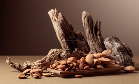 Téléchargez les photos : Noix d'amande dans un plat en bois sur fond brun. Nature morte avec des noix fraîches et de vieux chicots. - en image libre de droit