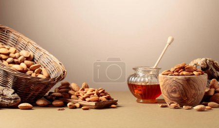Photo for Almond nuts in wooden dishes and honey in a glass jar. Copy space. - Royalty Free Image