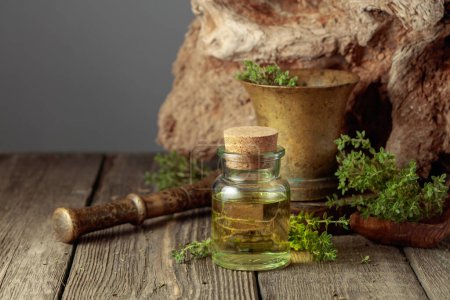 Photo for Bottle of thyme essential oil with fresh thyme twigs on an old wooden table. Copy space. - Royalty Free Image