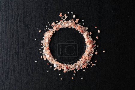 Photo for Pink Himalayan salt on a black ceramic table. Top view. - Royalty Free Image