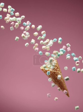 Photo for Small colorful marshmallows fall in a waffle cone on a pink background. Copy space. - Royalty Free Image