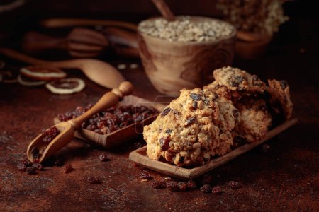 Téléchargez les photos : Biscuits au raisin d'avoine et ustensiles de cuisine sur une table brune. - en image libre de droit