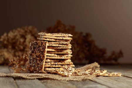 Téléchargez les photos : Crispy crackers with sunflower and flax seeds on an old wooden table. Simple healthy food. Copy space. - en image libre de droit