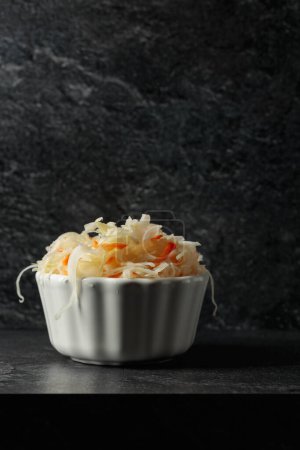 Téléchargez les photos : Bol de choucroute avec une carotte sur une table en pierre noire. Espace de copie. - en image libre de droit