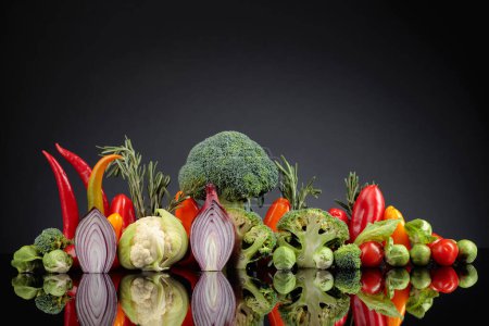 Téléchargez les photos : Divers légumes crus sur fond réfléchissant noir. Une image conceptuelle sur le thème du végétarisme. - en image libre de droit