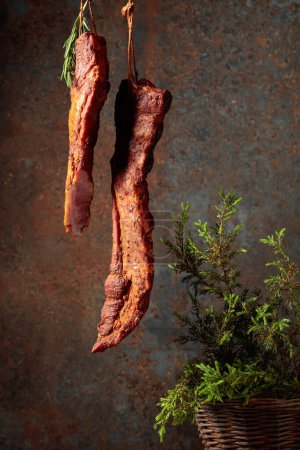 Photo for Homemade smoked pork ribs with juniper branches on a rusty background. Copy space. - Royalty Free Image