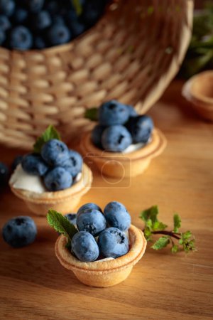 Téléchargez les photos : Petites tartelettes aux bleuets frais et menthe sur une table en bois. - en image libre de droit