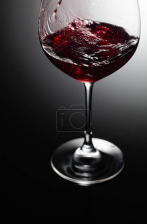 Foto de Primer plano del vino tinto vertiendo sobre un fondo negro. - Imagen libre de derechos