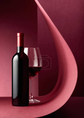 Téléchargez les photos : Bouteille et verre de vin rouge sur fond rouge. Espace de copie
. - en image libre de droit