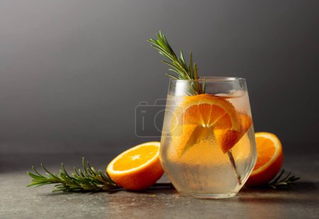 Téléchargez les photos : Cocktail gin tonic avec glace, romarin et orange sur une table en pierre. Espace de copie. - en image libre de droit