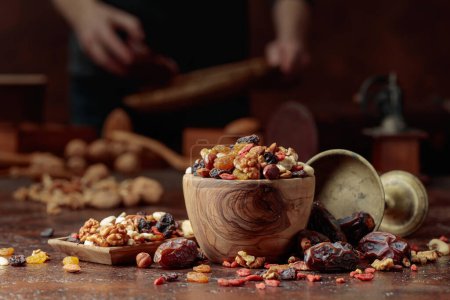 Téléchargez les photos : Divers fruits secs et noix sont dans un bol en bois sur une table de cuisine. Concentration sélective. - en image libre de droit