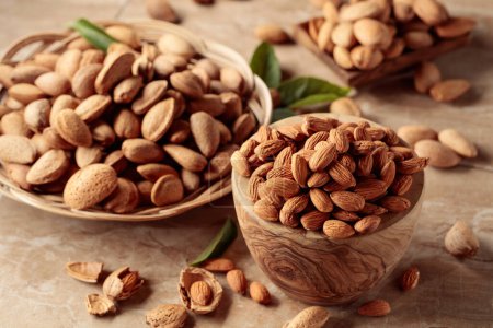 Photo for Almond nuts in wooden dishes on a brown ceramic table. - Royalty Free Image