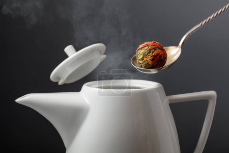 Téléchargez les photos : Boule de thé vert chinoise avec des fleurs de souci (calendula) sont versés dans la théière. Concentration sélective. - en image libre de droit