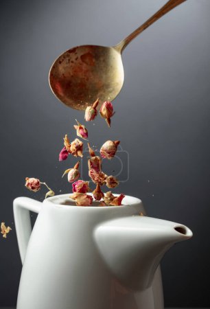 Photo for Dried rosebuds are poured into a white teapot. - Royalty Free Image