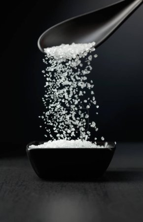 Photo for Sea salt is poured into a black bowl. Sea salt on a black background. - Royalty Free Image