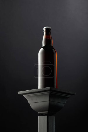Foto de Una botella de cerveza en un podio negro. Copiar espacio. - Imagen libre de derechos
