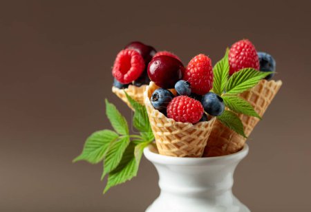 Foto de Colorida mezcla variada de arándanos, frambuesas y cerezas dulces en conos de gofre. - Imagen libre de derechos