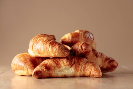 Photo for Freshly baked croissants on a beige ceramic table. Traditional French kitchen. - Royalty Free Image