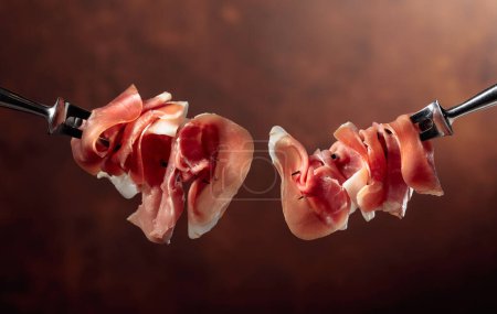 Photo for Thin slices of prosciutto on a fork. Copy space. - Royalty Free Image