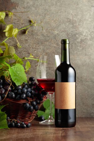 Téléchargez les photos : Verre et bouteille de vin rouge avec raisins bleus et branches de vigne. Sur une bouteille vieille étiquette vide. - en image libre de droit