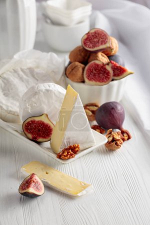 Photo for Camembert cheese with figs and walnuts on a white wooden table. - Royalty Free Image