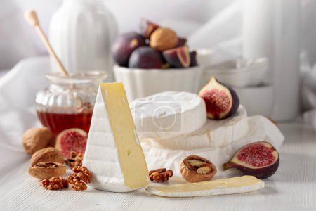Photo for Camembert cheese with figs, walnuts, and honey on a white wooden table. - Royalty Free Image