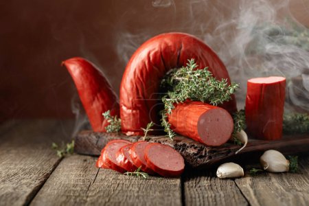 Photo for Smoked sausage with thyme and garlic. Sausage in natural smoke on a wooden table. - Royalty Free Image