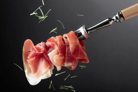 Photo for Thin slices of prosciutto on a fork. - Royalty Free Image