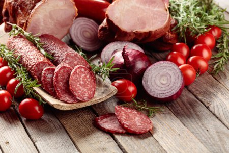 Photo for Food tray with delicious salami, ham, fresh sausages, tomato, and rosemary. Meat platter with a selection. - Royalty Free Image