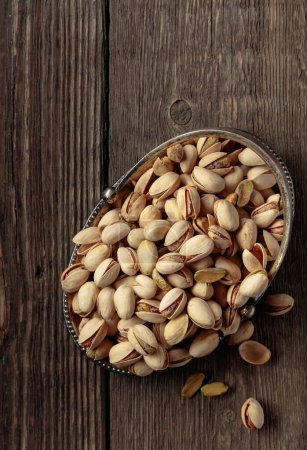Photo for Salted pistachios in a dish on an old wooden table. Top view. - Royalty Free Image