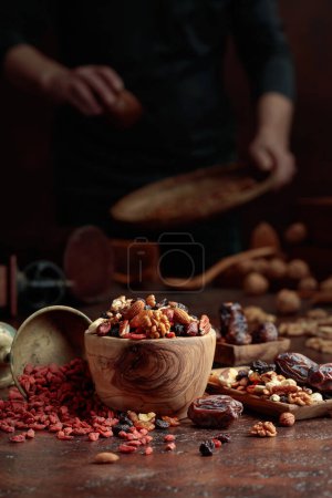 Téléchargez les photos : Divers fruits secs et noix sont dans un bol en bois sur une table de cuisine. Concentration sélective. - en image libre de droit
