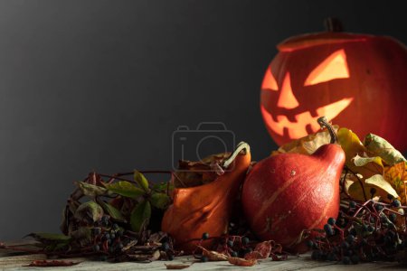 Téléchargez les photos : Halloween citrouille tête Jack lanterne avec des feuilles séchées. Halloween vacances art design, célébration. Citrouille d'Halloween sculptée avec bougie allumée. - en image libre de droit