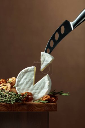 Photo for Brie cheese with walnuts, thyme, and rosemary on a wooden table. Copy space. - Royalty Free Image