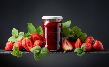 Photo for Strawberry jam and fresh berries with leaves on a black background. - Royalty Free Image