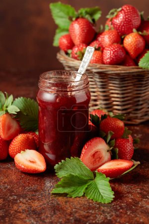 Photo for Strawberry jam and fresh berries with leaves on an old brown table. - Royalty Free Image