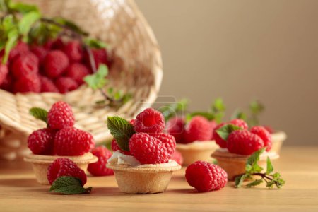 Photo for Small tartlets with fresh raspberries and mint on a wooden table. - Royalty Free Image