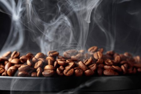 Téléchargez les photos : Steaming coffee beans on a black background. Selective focus. Copy space. - en image libre de droit