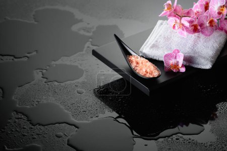 Téléchargez les photos : Belle floraison fleurs d'orchidée et rose sel de mer. Fond réfléchissant noir avec gouttes d'eau. - en image libre de droit