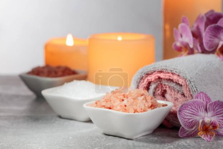 Foto de Sal marina, toallas, flores de orquídea y velas encendidas sobre un fondo gris. Concepto de spa con espacio para copiar. - Imagen libre de derechos