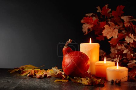 Foto de Bodegón con calabaza, hojas secas, velas encendidas y ramas de roble. Fondo negro con espacio de copia. Concepto de otoño. - Imagen libre de derechos