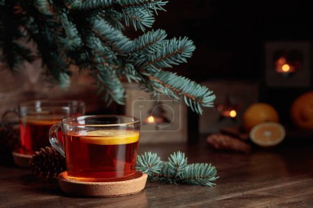 Foto de Té con limón y pequeñas linternas de Navidad con velas encendidas en una mesa de madera. - Imagen libre de derechos