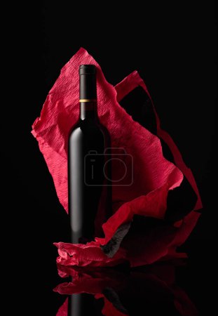 Téléchargez les photos : Bottle of red wine on a crumpled paper. Black reflective background. - en image libre de droit