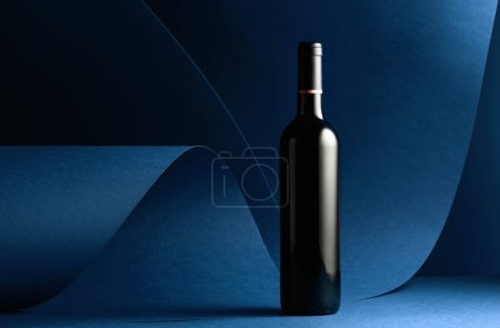 Photo for Bottle of red wine on a blue background. Copy space. - Royalty Free Image