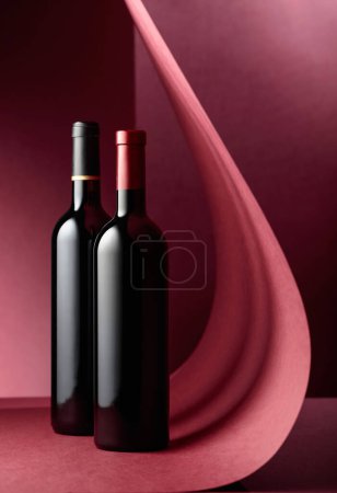 Photo for Bottles of red wine on a red background. Copy space - Royalty Free Image