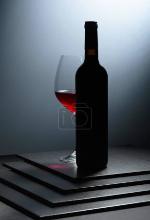 Foto de Botella y copa de vino tinto sobre una mesa negra. - Imagen libre de derechos