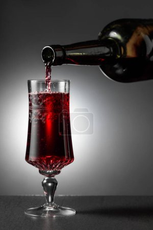 Dessert wine or liqueur is poured into a glass from an ancient bottle. Copy space.