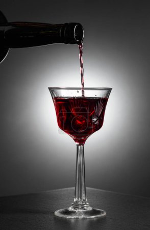 Foto de El vino de postre o licor se vierte en un vaso de una botella antigua. Copiar espacio. - Imagen libre de derechos