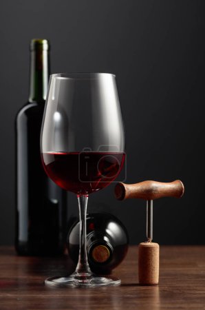 Photo for Red wine and corkscrew on an old wooden table. - Royalty Free Image