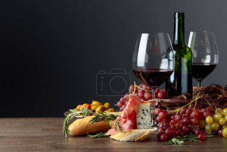 Photo for Sandwich with prosciutto, blue cheese and rosemary on a dark background. Delicious snack and red wine. Copy space. - Royalty Free Image