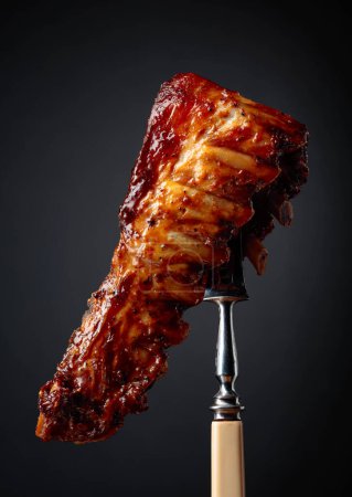 Téléchargez les photos : Côtes de porc grillées sur une fourchette. Fond noir
. - en image libre de droit